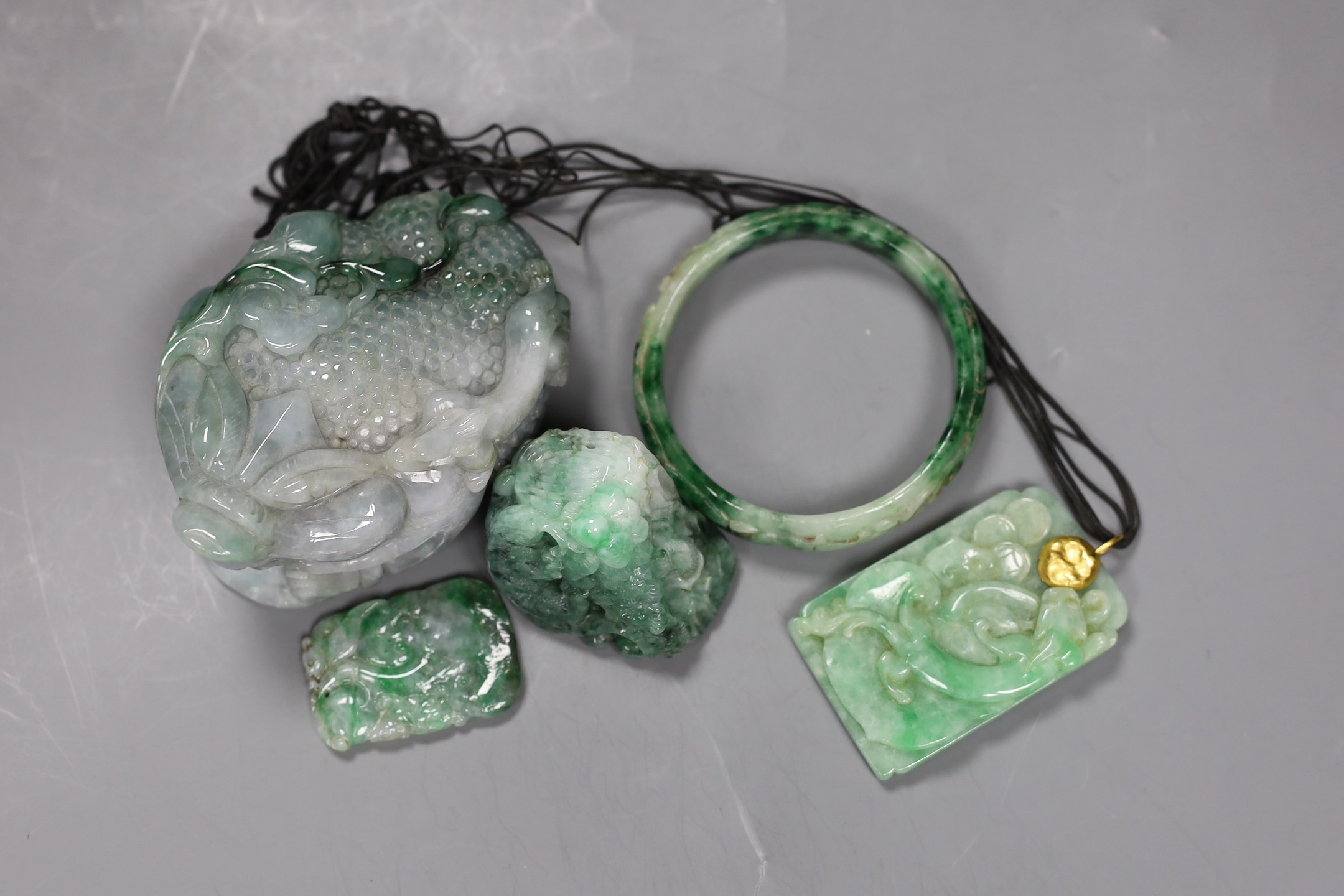 A group of five Chinese jadeite carvings, including two pendants and a bangle, largest 11cms long